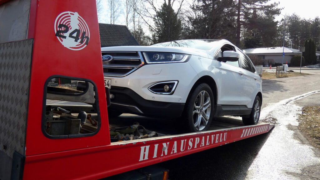 Valkoinen henkilöauto hinausauton kyydissä
